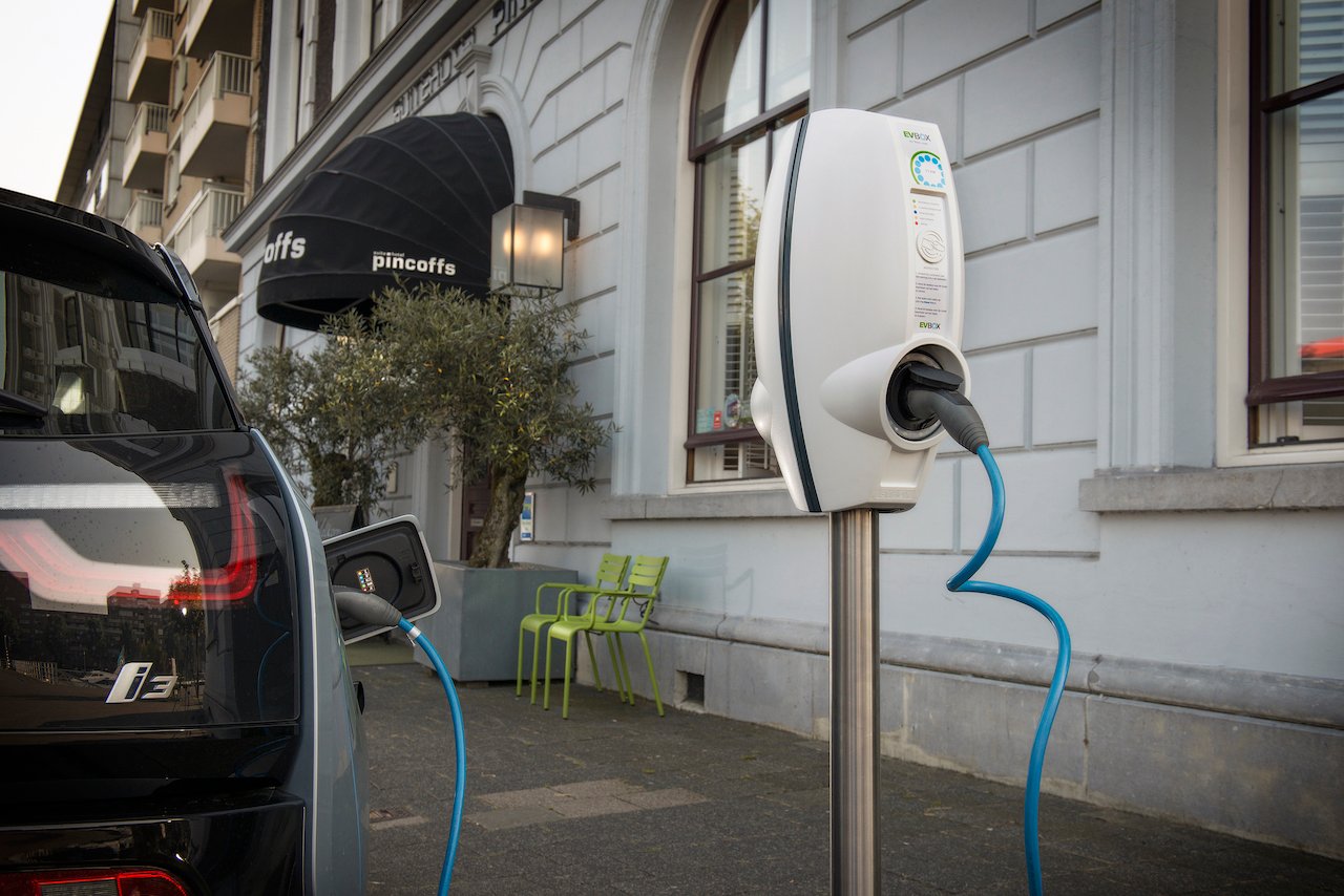 bmw i3 elektrische auto aan het laden bij een evbox businessline laadpaal op straat naast een hotel