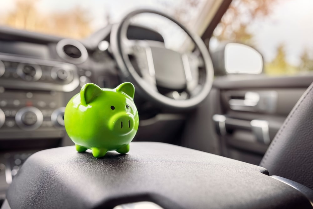 A green piggybank in the driver seat of a vehicle.