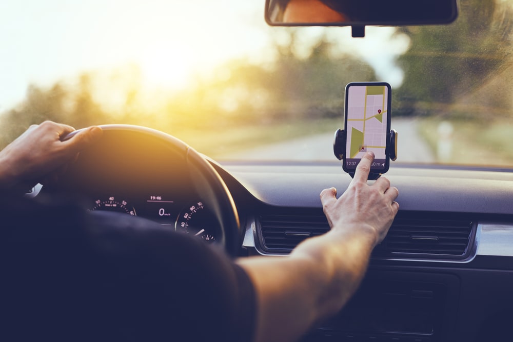 A driver checking the hands-free navigation app while driving on a sunny day.