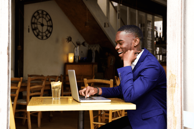 Man in blue suit smiling at laptop about the astonishing facts which he just learned.