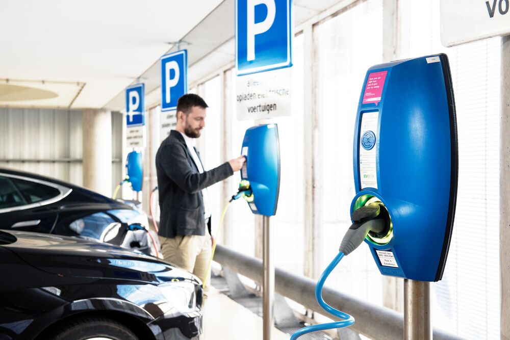 Four EVBox BusinessLine charging stations at an indoor parking lot at a business. A man pays at one of the charging stations.