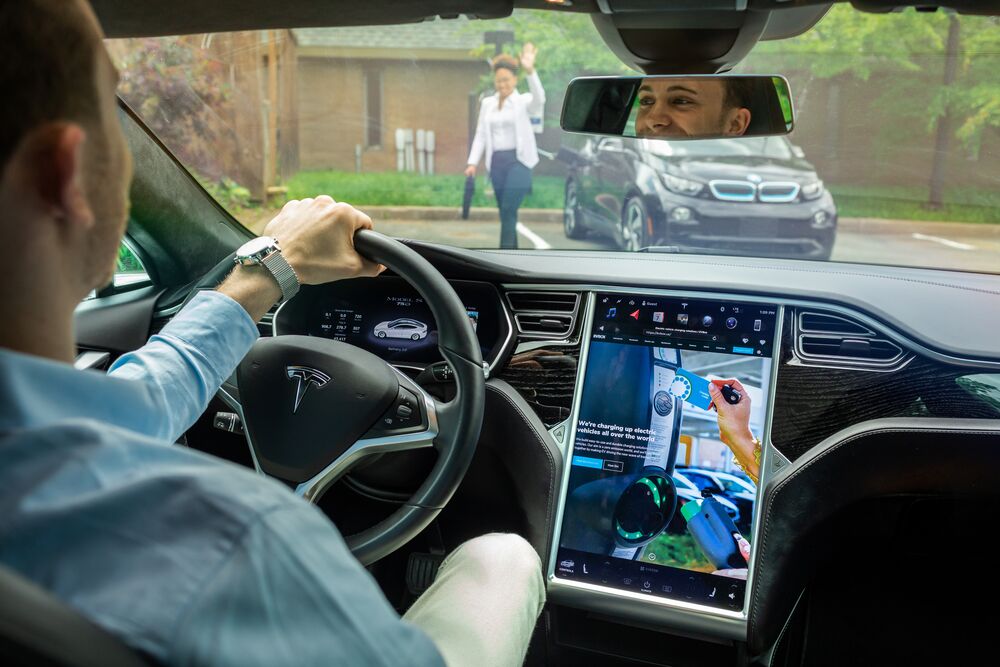 Interior of Tesla being driven. In the screen, it shows information about charging at a EVBox charging station.