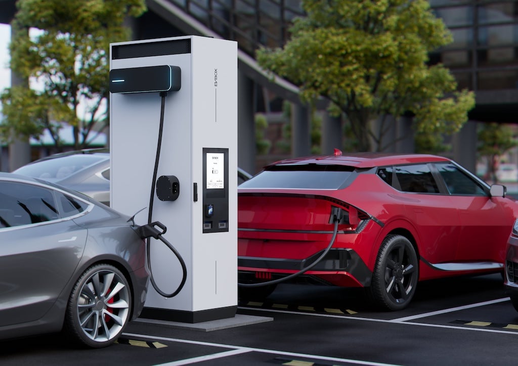 Two electronic vehicles are being charged at an EVBox Troniq Modular High Power DC charging station..