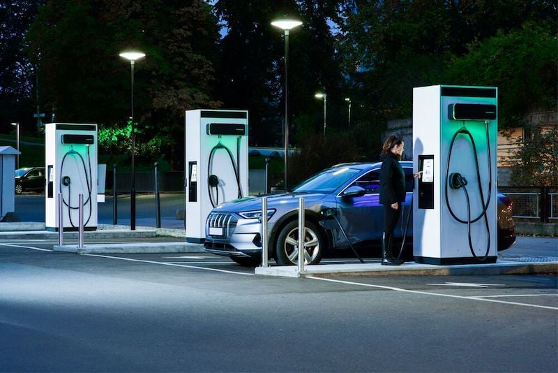 A woman is charging her EV at night at EVBox Troniq Modular fast charging station.