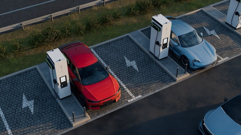 A red EV and a blue EV are being charged by EVBox Troniq Modular charging stations.