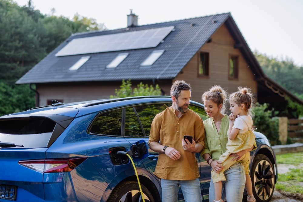 A family standing next to their car that's charging on solar power.