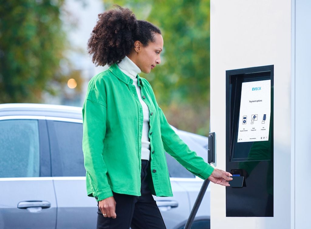 A woman paying for her fast-charging session at an EVBox Troniq Modular DC charging station.