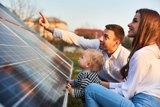 A family of three are looking at solar panels.