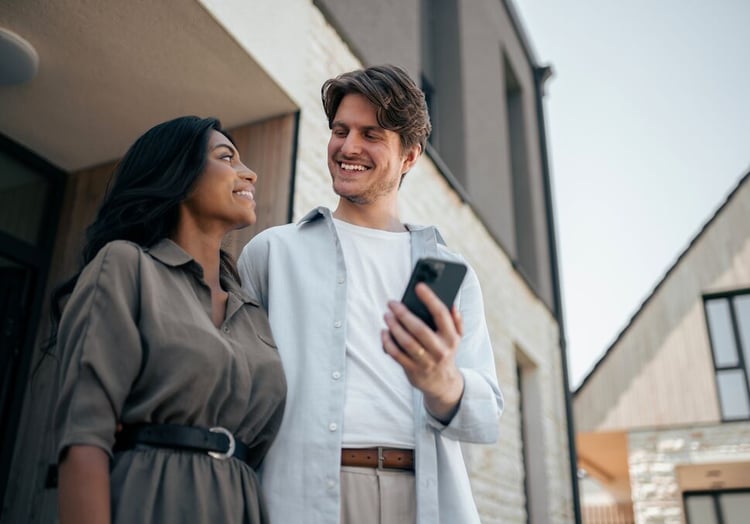 A couple smiling at each other while looking up their current utility bill.
