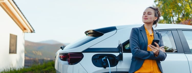 A woman waiting for her car to be charged with solar panels installed at her home.