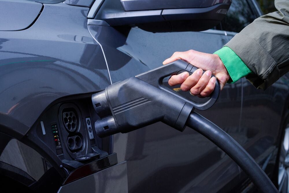 Driver plugs a DC fast-charging cable and plugs it into her electric vehicle. 