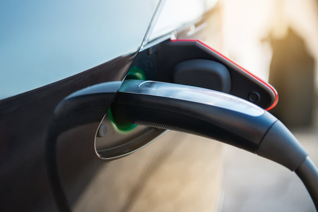 A Tesla charger plug charging a Tesla EV