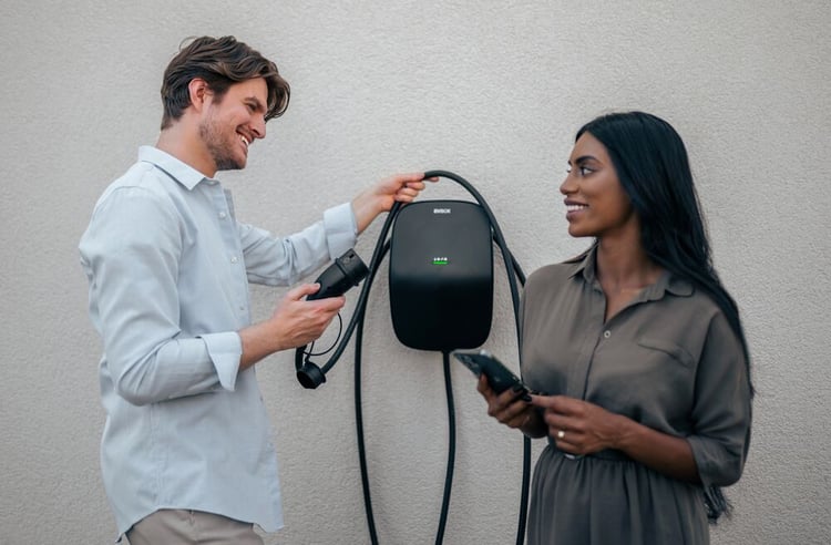 A couple standing in front of their EVBox Livo home charging station.