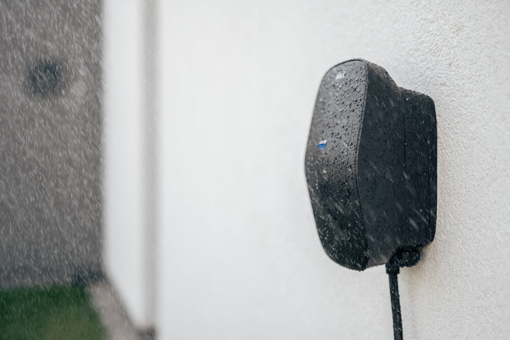 a wall-mounted EVBox Livo home EV charging station in the rain.