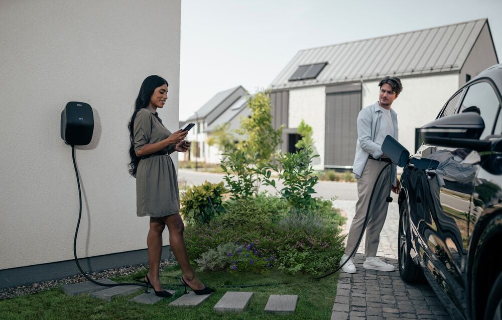 A couple using their EVBox Livo home charging station to charge their car safely.