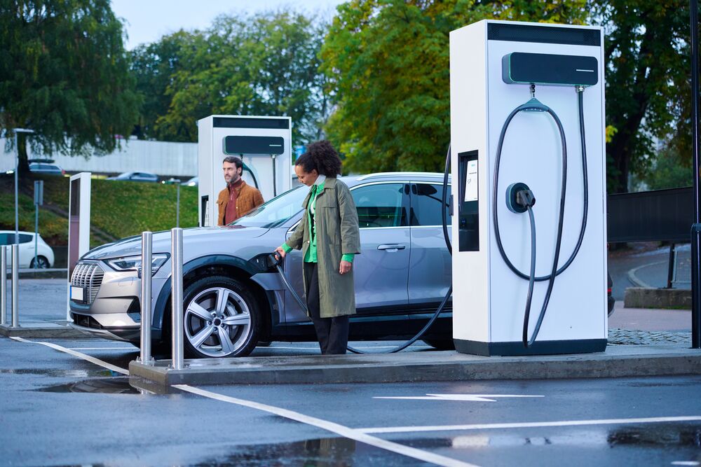 Woman charging her car using the EVBox Troniq Modular. A man is standing on the other side of the car.