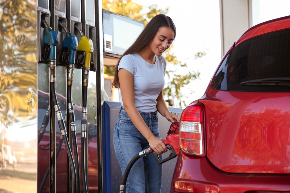 A woman refuels her vehicle at a gas pump at a gas station.