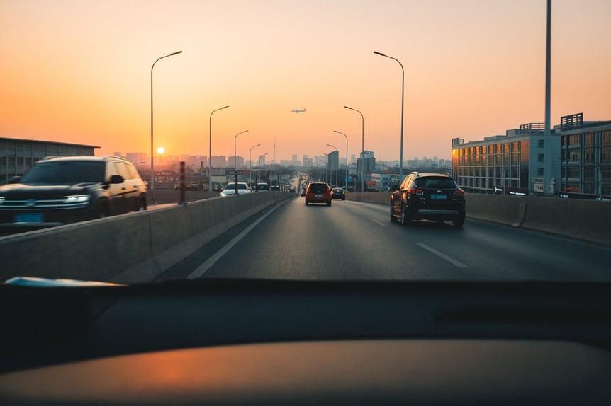 Aufnahme vom Inneren eines Autos während der Fahrt auf einer Autobahn bei Sonnenuntergang.