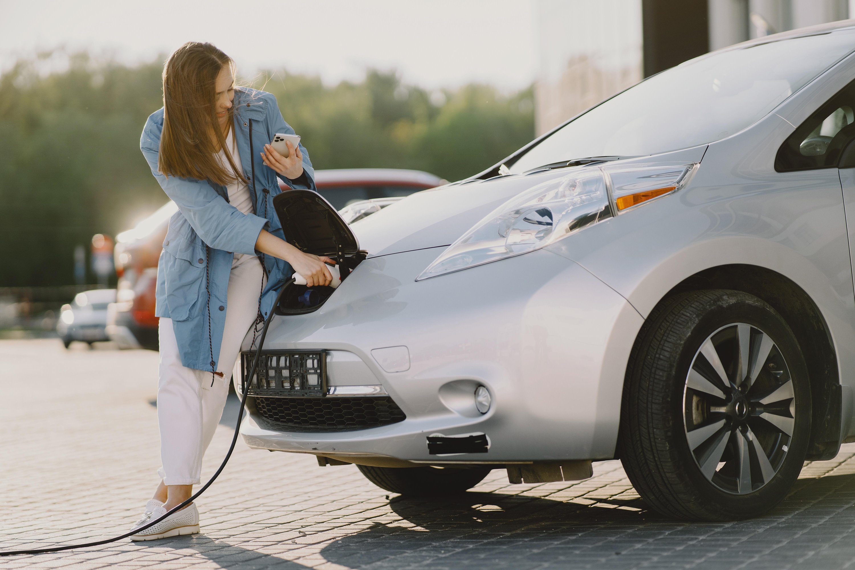 Woman smiling and charging electric car.