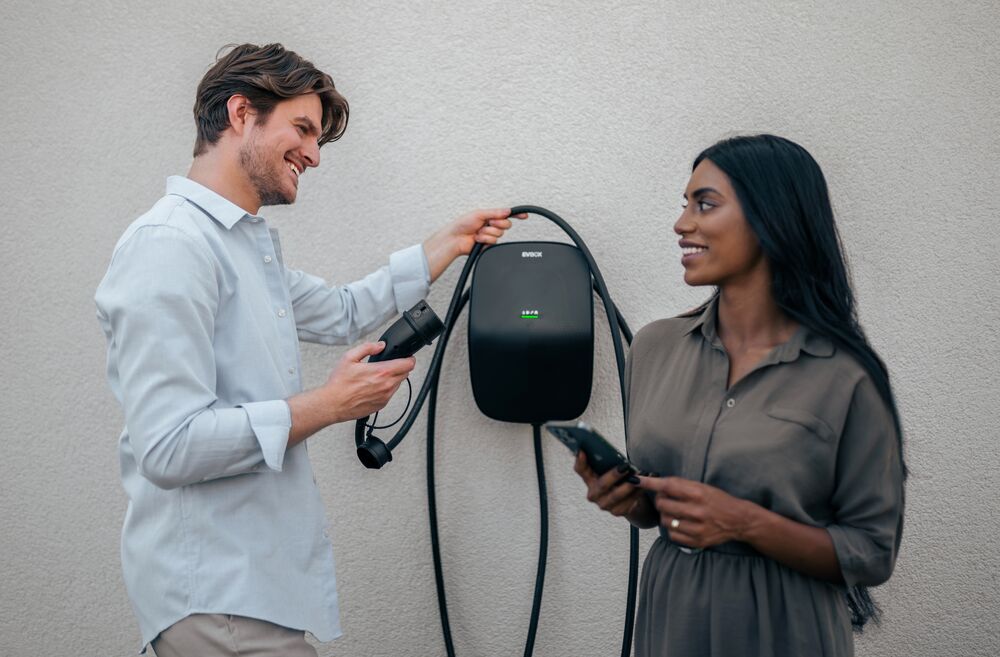 Couple smiling while man holds cable of EVBox Livo.