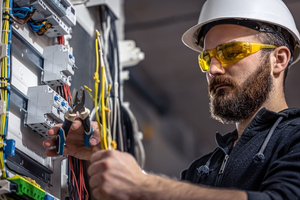 An electrician wearing safety goggles and a helmet while upgrading the meterbox.