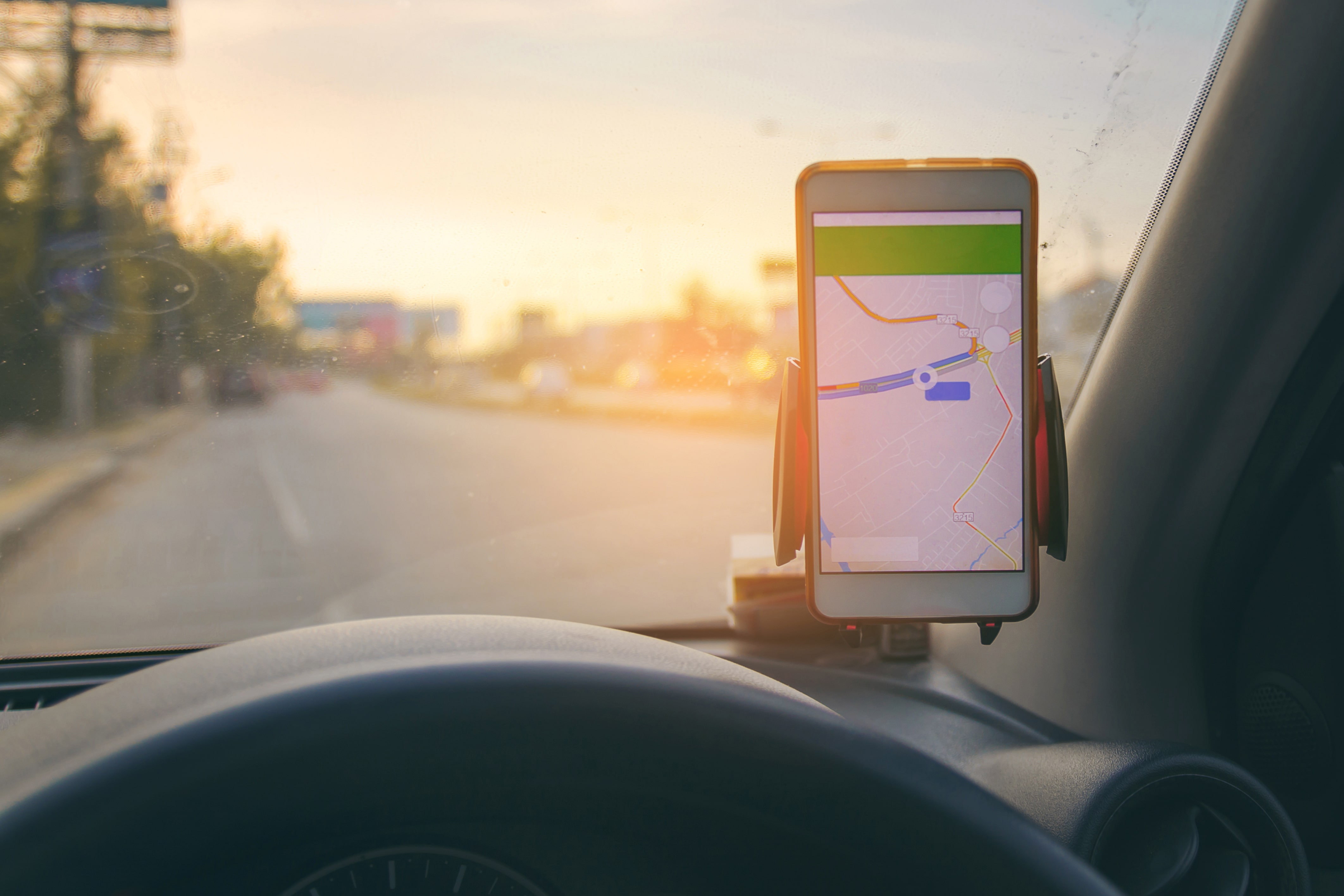 A smart phone in a car holder showing a route on Google Maps/
