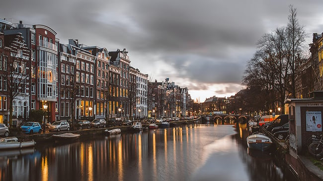 The canals in Amsterdam at dawn with streetlights reflecting in the water