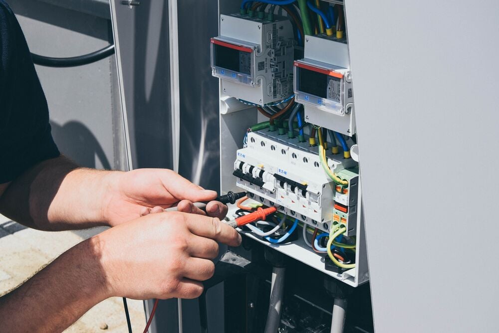 A closeup of a person who is repairing the electrical panel of an EVBox charging station.
