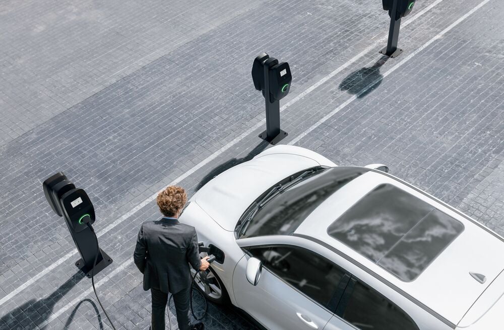 An aerial shot of a business man charging his car with an EVBox Liviqo AC charging station.