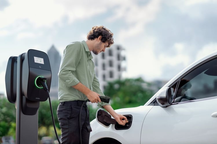 A man charging his car at the office with an EVBox Liviqo AC charging station.