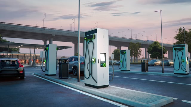 EVBox Troniq Modular naast tankstation tijdens zonsondergang met elektrische auto's