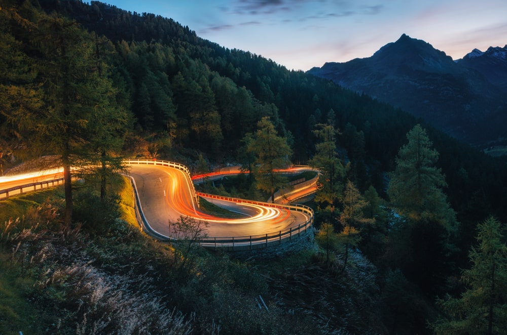 Zooming lights on a winding mountain road at twilight 