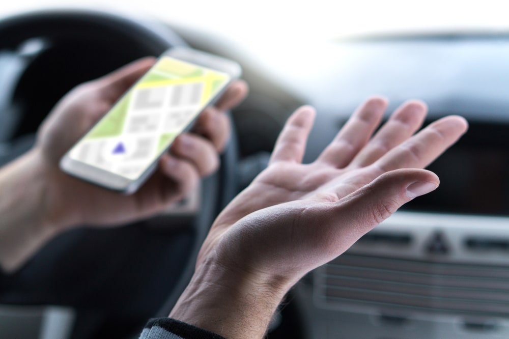 A close-up view of a man using his navigation app on his smartphone in his EV