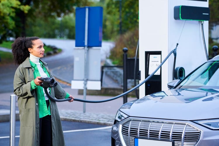 Woman pulls the cable from the cable management system of EVBox Troniq Modular to charge her EV.  