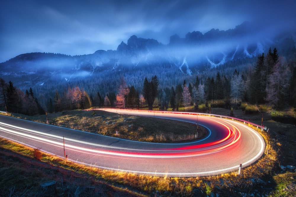 A winding mountain road at night with zooming lights