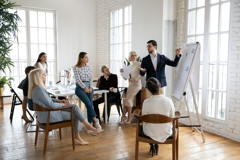 Man conducts a workplace meeting in a relaxed space with his coworkers.