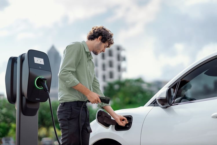 Man uses an EVBox Liviqo AC charging station to charge his electric car.