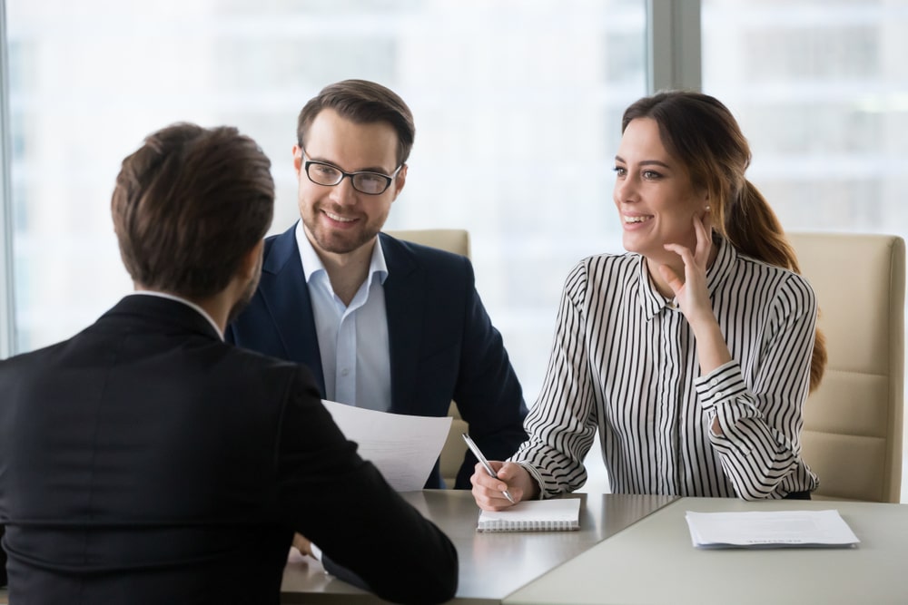 Woman and man smiling while interviewing male job candidate.