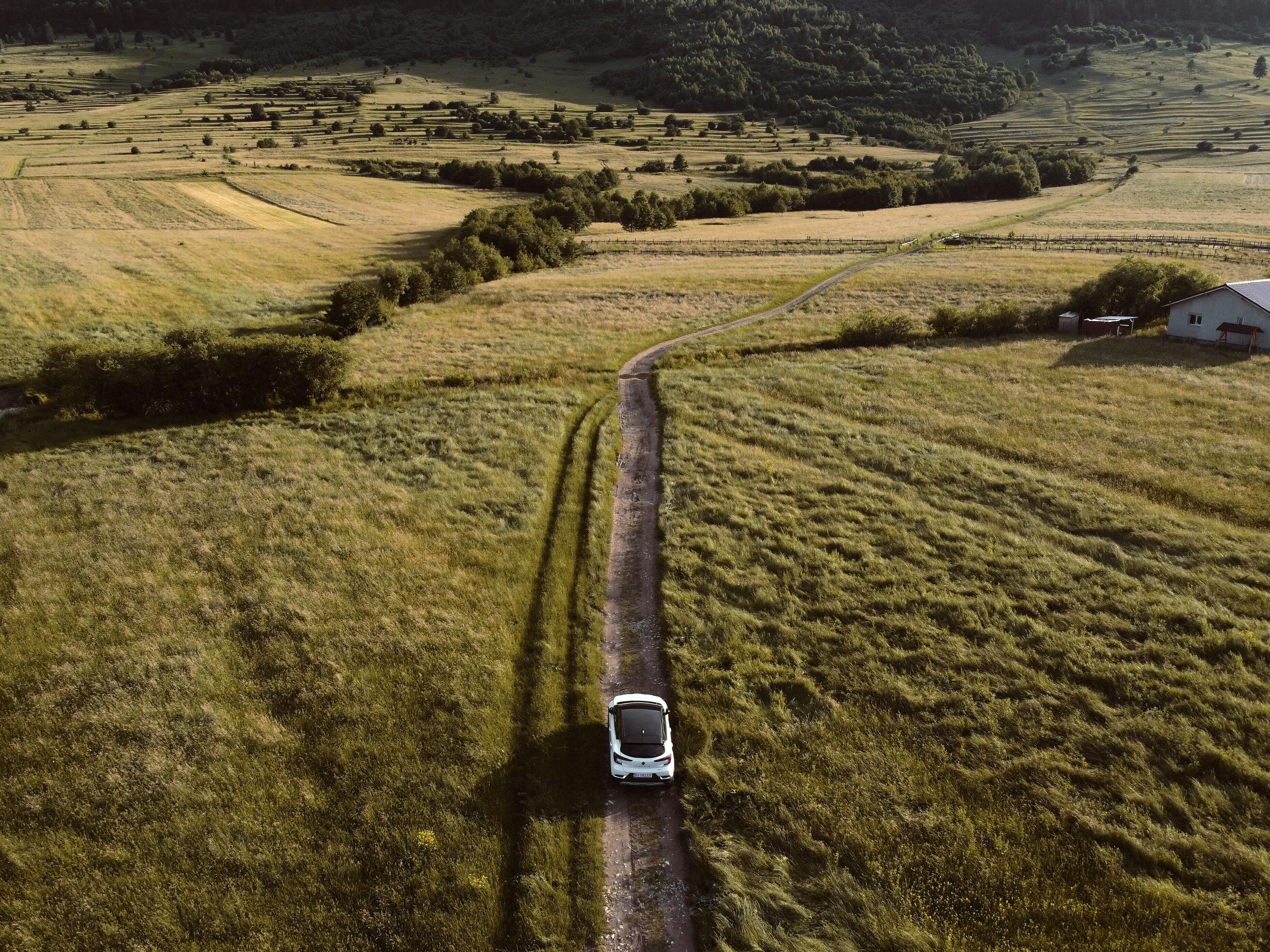 Eine flächige Aufnahme eines Elektroautos, das auf einem Feldweg inmitten einer üppigen Landschaft fährt.