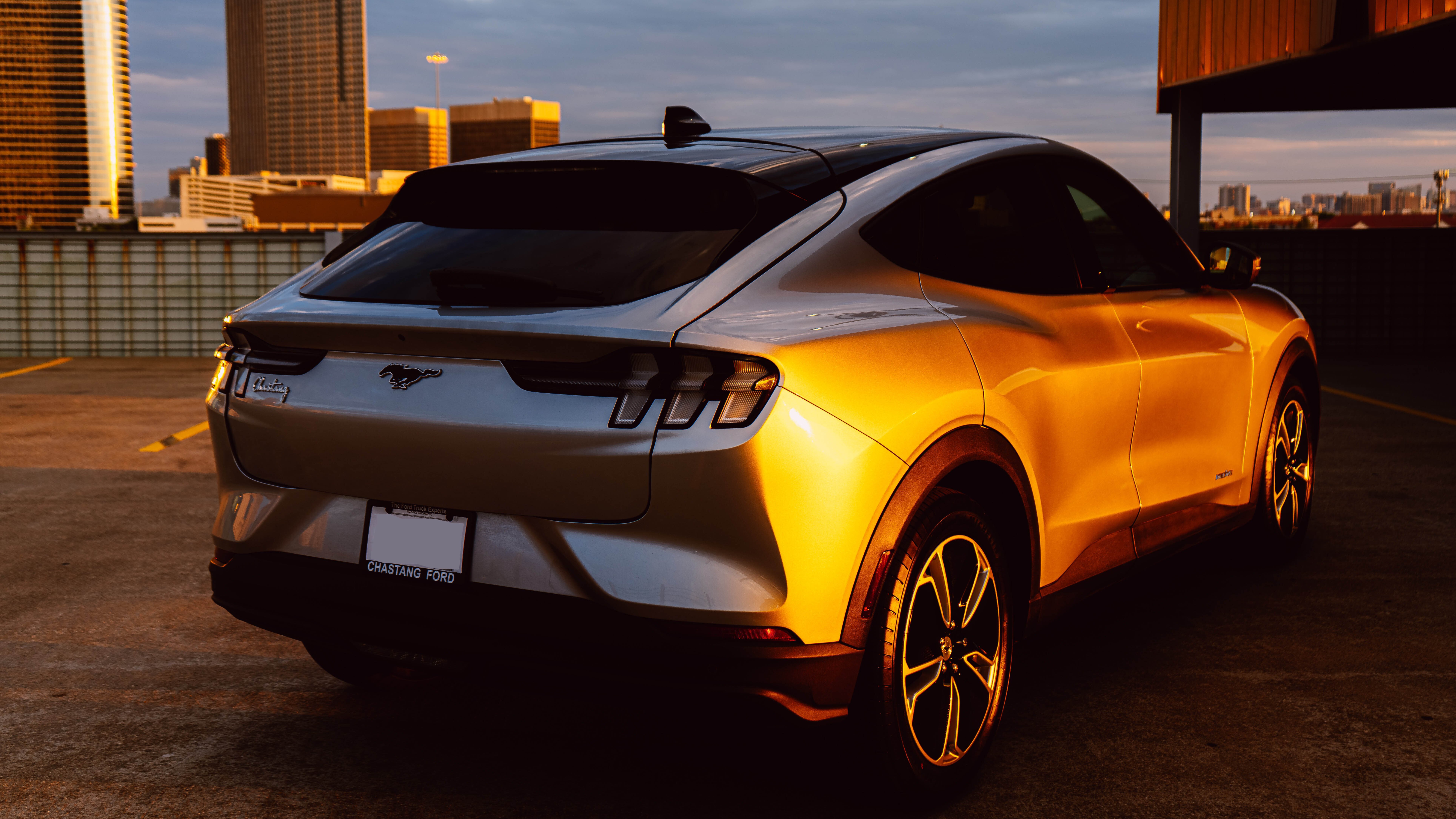 Ein Ford Mustang Mach-E, geparkt auf einem Dachparkplatz während des Sonnenuntergangs.