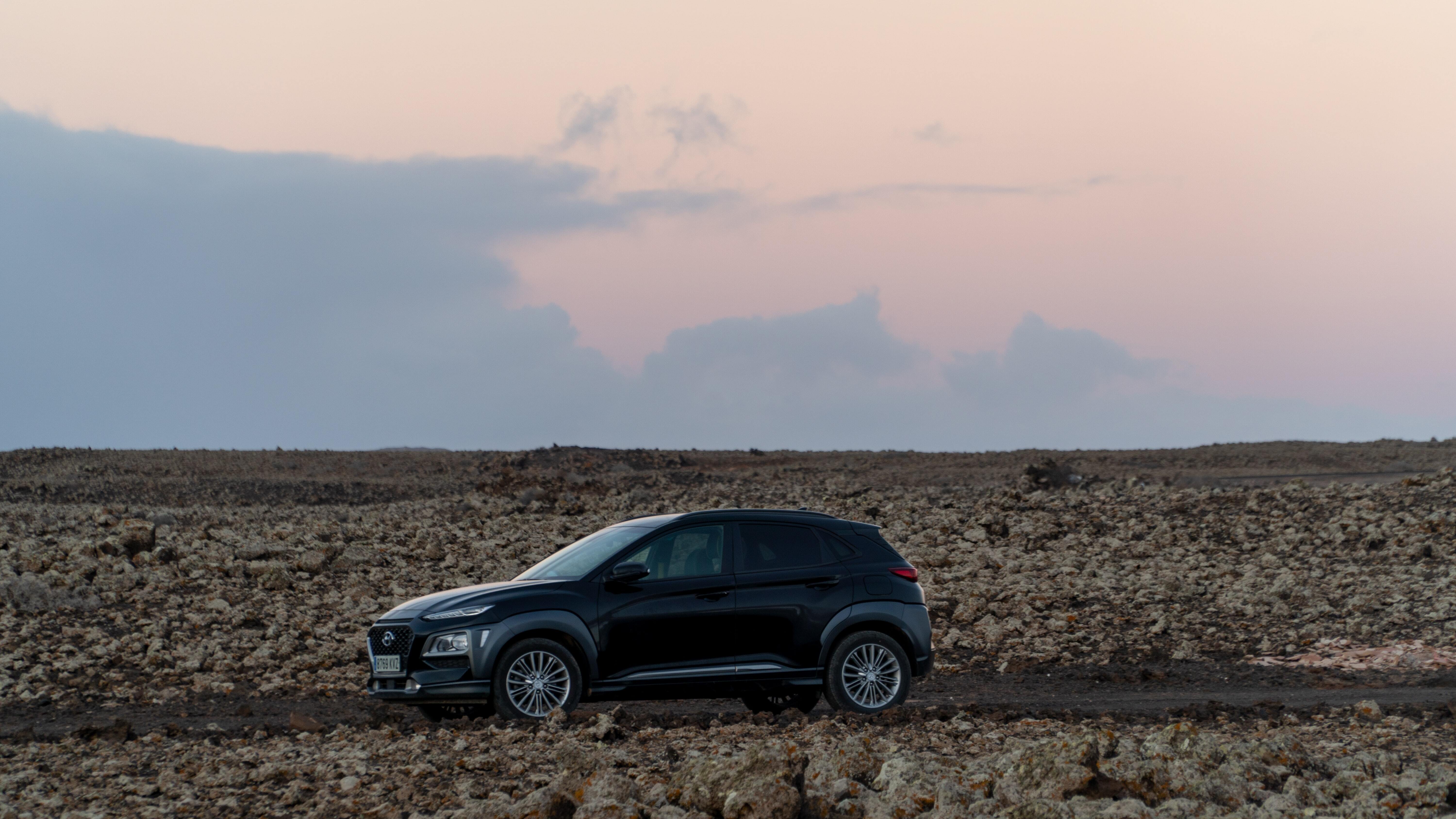 A Hyundai Kona parked in a barren area during sunset.