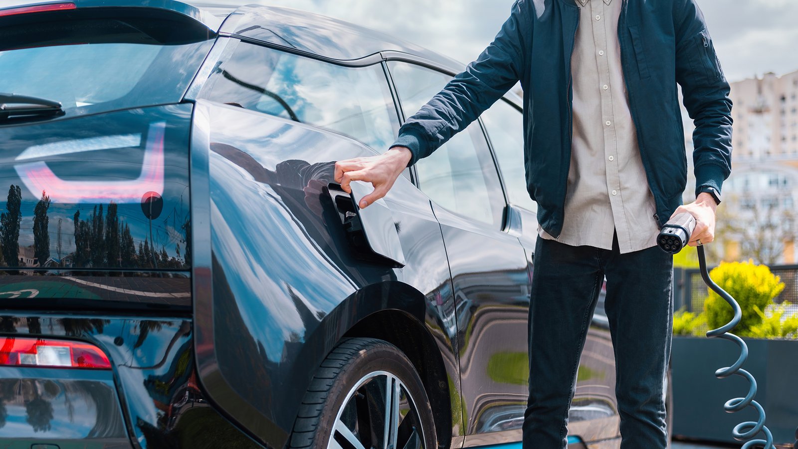 Un homme s'apprêtant à charger son véhicule électrique en ouvrant la petite porte pour accéder à la prise