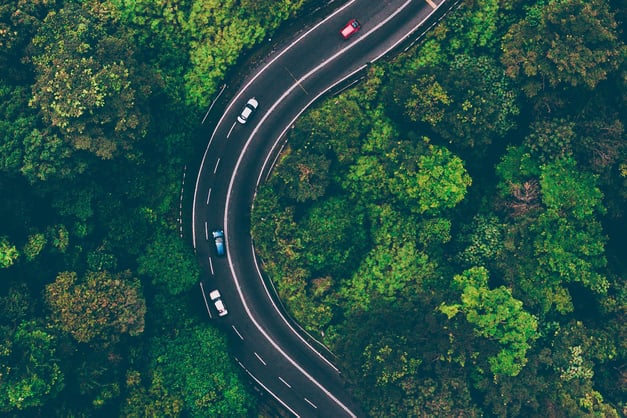 Plan aérien d'une autoroute sinueuse à trois voies dans la forêt. 