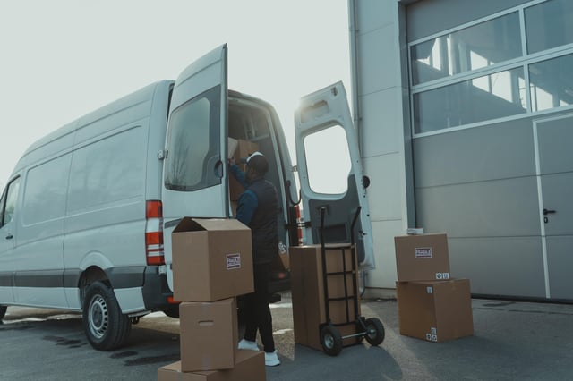 Trabajador de una empresa de reparto, cargando cajas en su furgoneta.