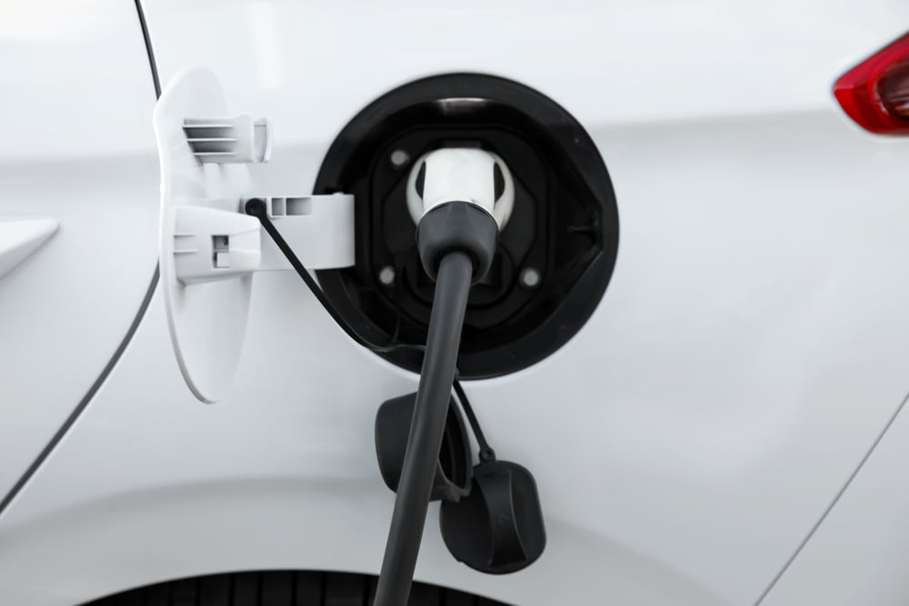 A closeup of a white electric car plugged in and charging.