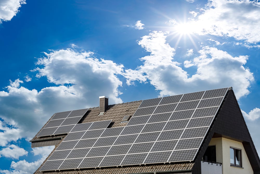 Ein Schrägdach eines modernen Hauses mit einer Reihe von Solarzellen, die an einem sonnigen Tag Strom erzeugen.