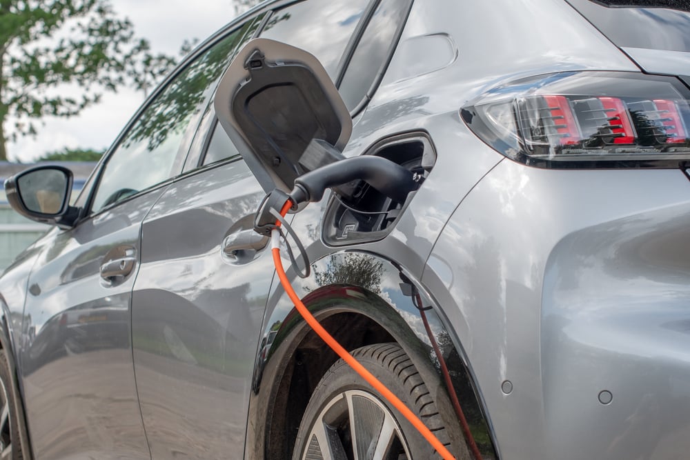 A closeup of a grey electric car charging.