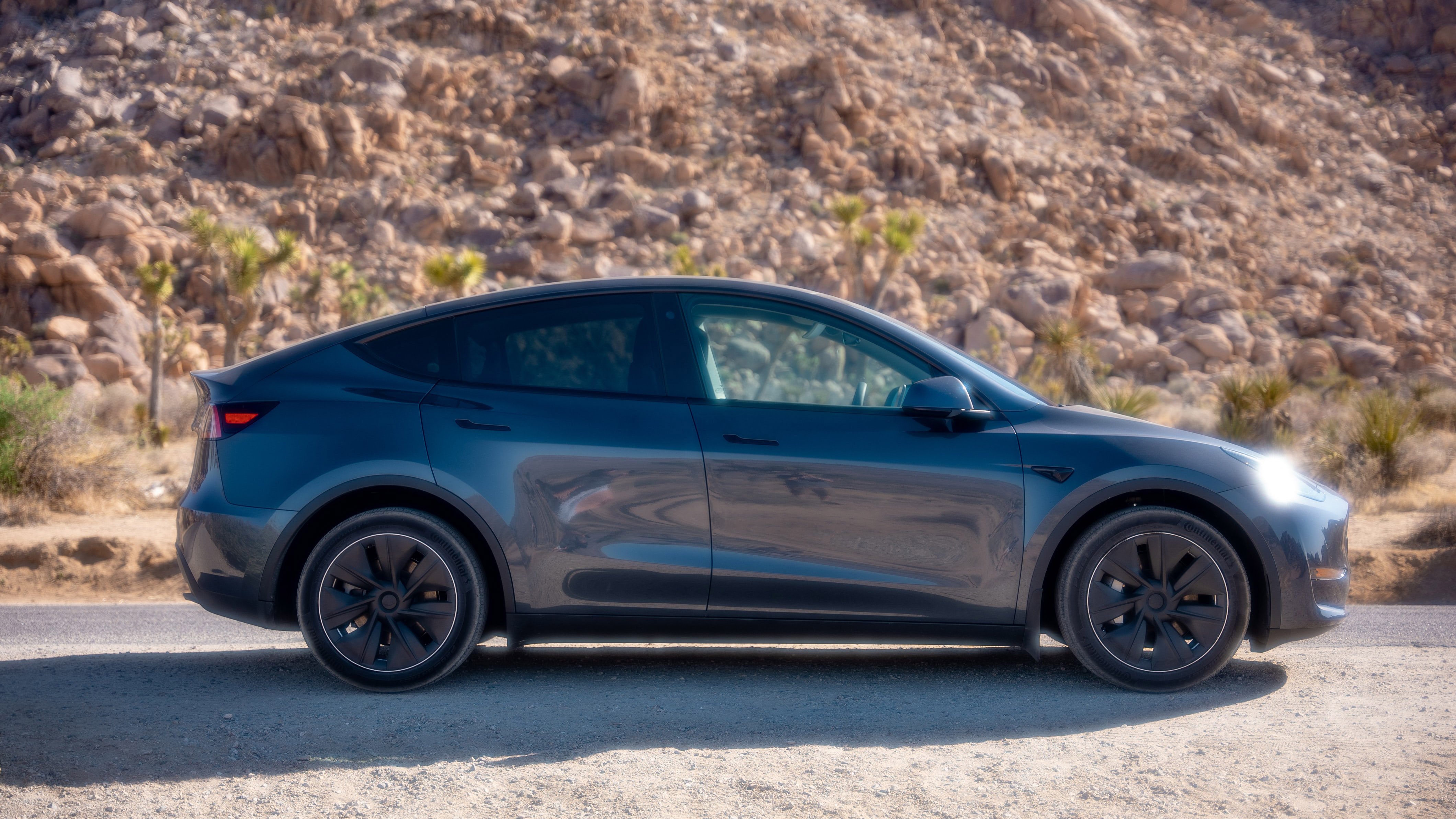 A Tesla Model Y parked in a rocky landscape.